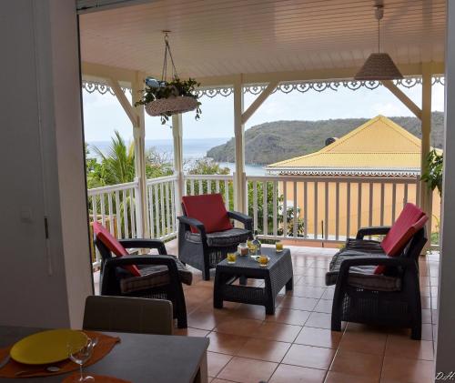 a screened in porch with chairs and a table at Villa Nord-Plage in Les Anses-dʼArlets