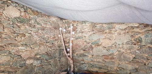 un coin d'un mur en pierre avec un rideau blanc et un mur en pierre dans l'établissement U paliaghju, une cabane de berger pour vivre un dépaysement total, à Santa-Lucia-di-Mercurio