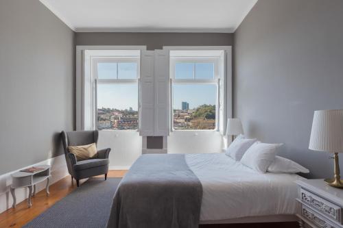 a bedroom with a bed and a chair and two windows at GuestReady - Astern Innvict - Street view in Porto