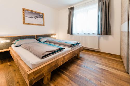 a bedroom with a wooden bed in a room with a window at Appartment Sorgenfrei in Altenmarkt im Pongau