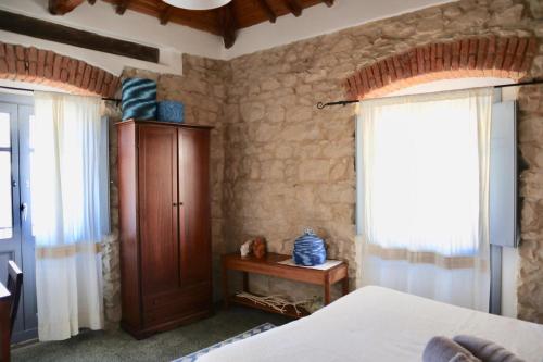 a bedroom with a bed and a cabinet and a window at Drommire In Plassa E Clesia in Baunei