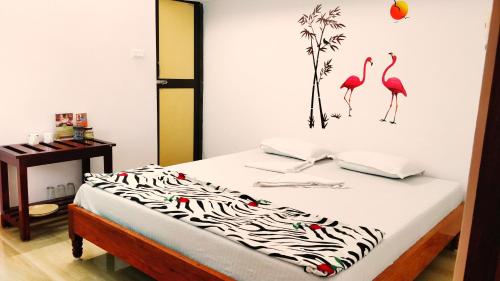a bedroom with a bed with flamingos on the wall at Blue Bridge Homes in Port Blair