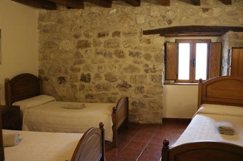 a bedroom with two beds and a stone wall at Albergue El Puntido in Hontanas