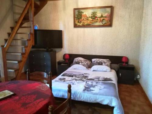 a bedroom with a bed and a television and stairs at Studio duplex 2 Lac des Montagnès in Mazamet