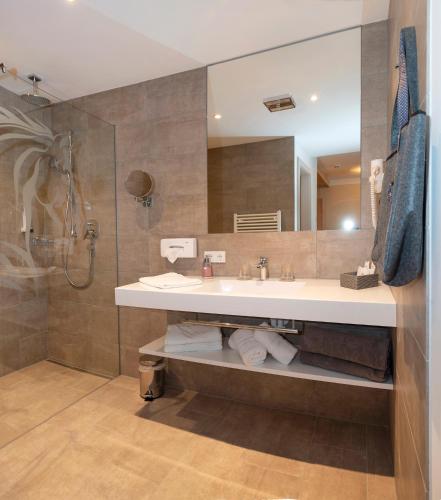 a bathroom with a sink and a large mirror at Hotel Der Wastlhof - Pools, Spa & eigene Reitschule in Niederau