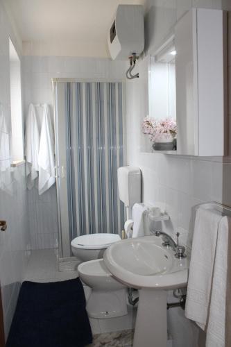 a white bathroom with a toilet and a sink at Villa Paola Holidays in Sciacca