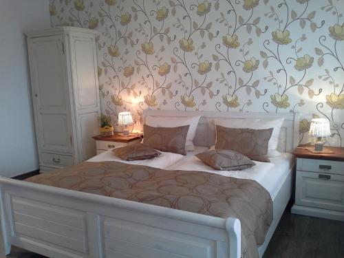 1 dormitorio con cama blanca y papel pintado con motivos florales en Gasthaus Hinterländer Schweiz, en Gladenbach
