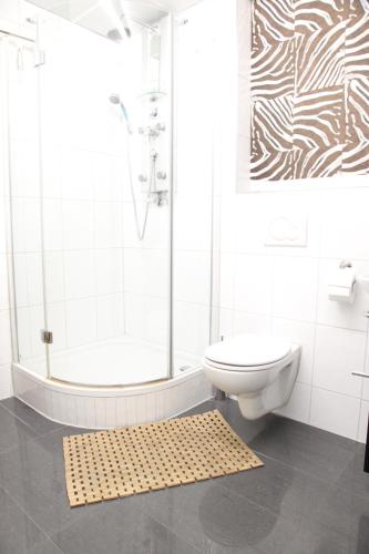 a white bathroom with a shower and a toilet at Sleep Well Rooms in Stuttgart