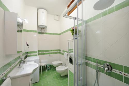 un bagno verde e bianco con due servizi igienici e un lavandino di Amalfi Blue FLowers B ad Amalfi