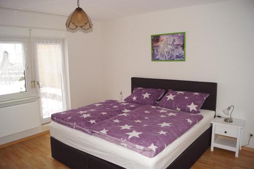 ein Schlafzimmer mit einem Bett mit einer lila Bettdecke in der Unterkunft Ferienwohnung Schuppener in Puderbach