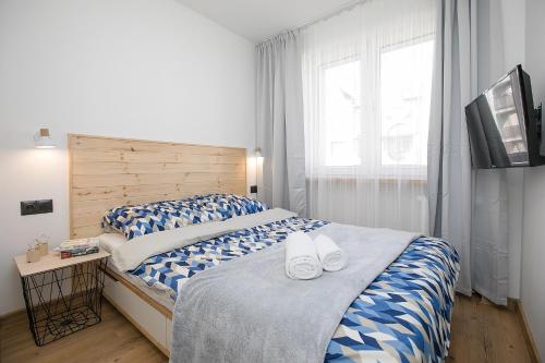 a bedroom with a large bed with blue and white sheets at Studio 49 Apartment in Ełk