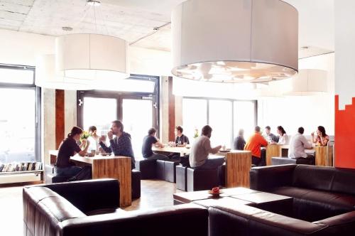a group of people sitting at tables in a restaurant at Five Elements Hostel and Capsules Frankfurt in Frankfurt/Main