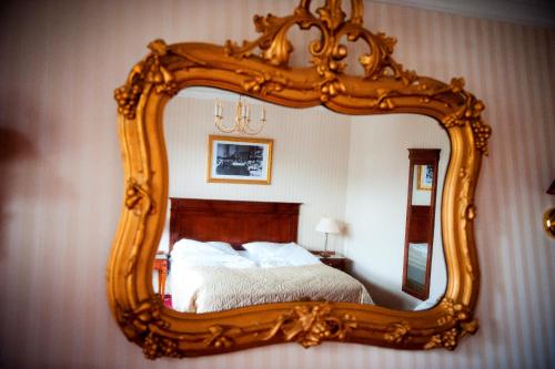 a mirror with a wooden frame in a bedroom at Fleischer's Hotel in Vossevangen