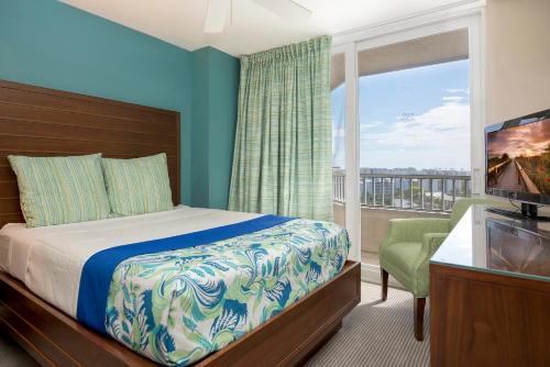 una camera con letto e un balcone con TV di GullWing Beach Resort a Fort Myers Beach