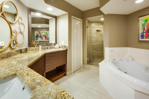 a bathroom with a tub, sink, mirror and bathtub at GullWing Beach Resort in Fort Myers Beach