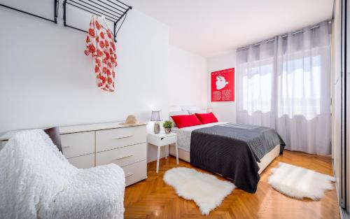 a white bedroom with a bed and a chair at Apartment Cookie in Pula