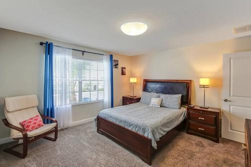 a bedroom with a bed and a chair and a window at F - New 4 Bedroom Home - 5 Miles to Disney - Free Water Park - Private Pool in Kissimmee