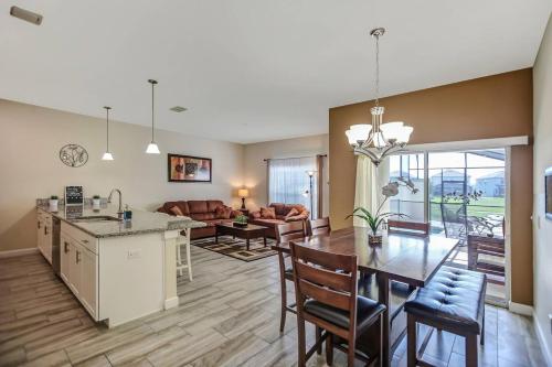 a kitchen and living room with a table and a dining room at F - New 4 Bedroom Home - 5 Miles to Disney - Free Water Park - Private Pool in Kissimmee