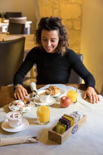a woman sitting at a table with plates of food at Il Cortiletto Hotel Maison in Tresnuraghes