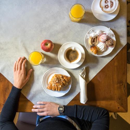 a person sitting at a table with breakfast foods at Il Cortiletto Hotel Maison in Tresnuraghes