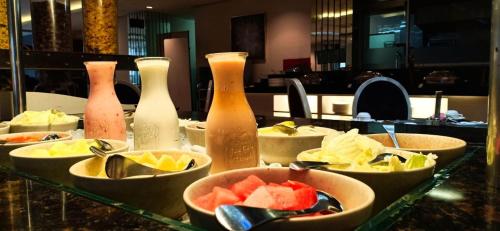 a buffet with bowls of fruit and bottles on a table at Gino Feruci Braga by KAGUM Hotels in Bandung