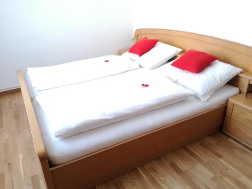 Una cama con dos almohadas rojas encima. en Pension Geschriebenstein en Lochenhaus