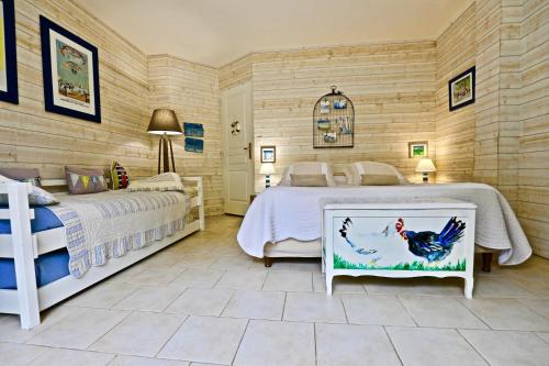 a bedroom with two beds and a chicken picture at La Longère in Bonneville-sur-Touques