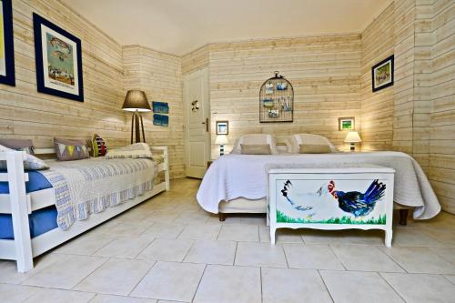 a bedroom with two beds and a chicken picture at La Longère Deauville in Bonneville-sur-Touques