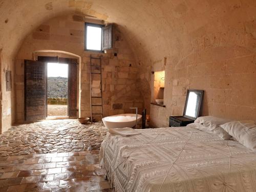 um quarto com uma cama e uma banheira num quarto em Sextantio Le Grotte Della Civita em Matera