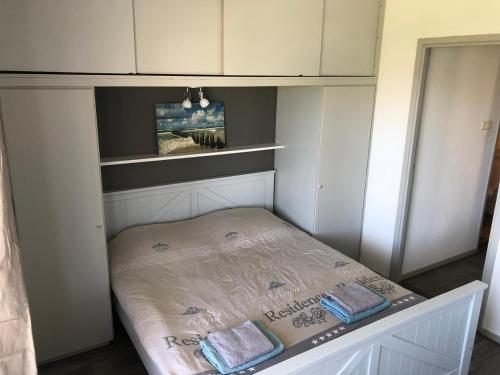 a small bed in a room with white cabinets at Appartement Dishoek in Koudekerke
