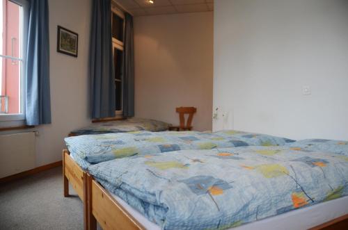 a bedroom with a bed with a blue comforter at Hotel Restaurant Bahnhof in Schüpfen