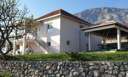 a white house with a stone wall in front of it at Uphill Glavanovic Villas in Bar