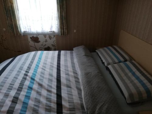 a bed in a small room with a striped comforter at Izerski Poranek in Gryfów Śląski