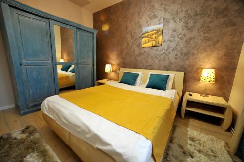 a bedroom with a large bed with yellow sheets and blue pillows at Like Home in Braşov