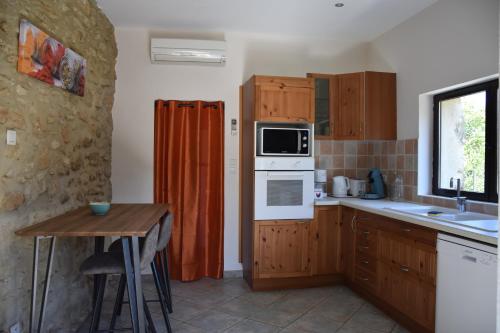 - une cuisine avec des placards en bois, une table et un four micro-ondes dans l'établissement Gîte La Lichère - Le Romarin, à Saint-Montan