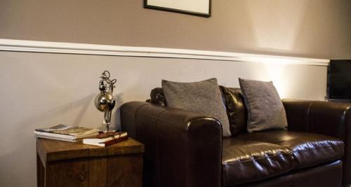 a living room with a brown leather couch and a table at Home Farm Apartments in Portree