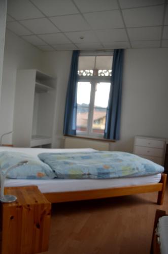 a bedroom with a bed and a window with blue curtains at Hotel Restaurant Bahnhof in Schüpfen