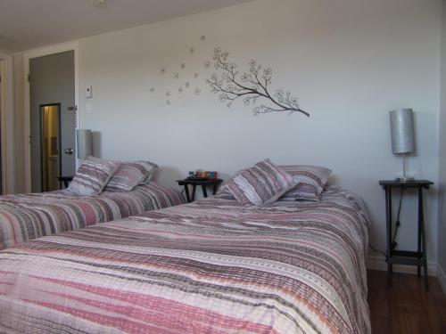 - une chambre avec 2 lits et des couettes rayées dans l'établissement Hostellerie du Suroît, à Beauharnois