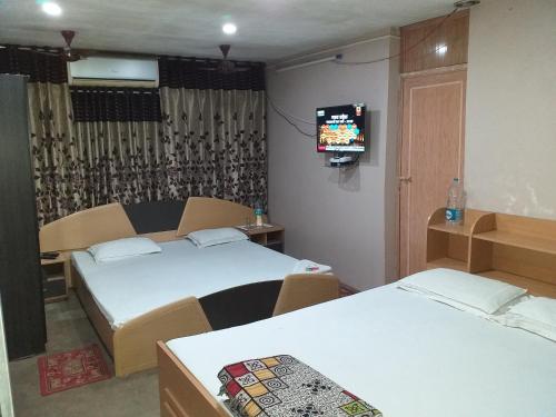 Cette chambre comprend 2 lits et une télévision. dans l'établissement Royal Guest House, à Kolkata