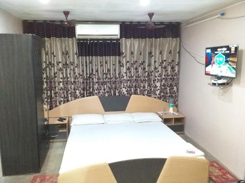 a bedroom with a white bed and a television at Royal Paying Guest in Kolkata