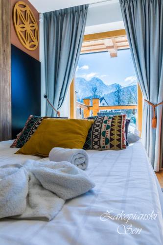 a bedroom with a bed with blue curtains and a window at Rezydencja Zakopiańska in Zakopane