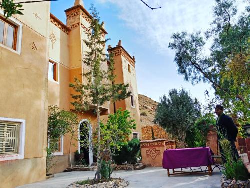a man walking past a house with a purple chair at Riad Kasbah des Roches in Akhendachou nʼAït Ouffi