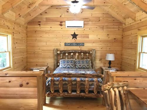 a log cabin bedroom with a bed in it at Pine Creek Cabins & Camping Resort in South Bloomingville