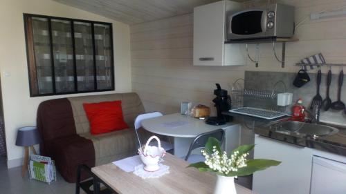 uma sala de estar com um sofá e uma mesa numa cozinha em Le Petit Logis em Puy-du-Fou