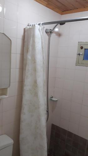 a shower with a white shower curtain in a bathroom at La Posada de Pinky Hotel in Puerto Santa Cruz