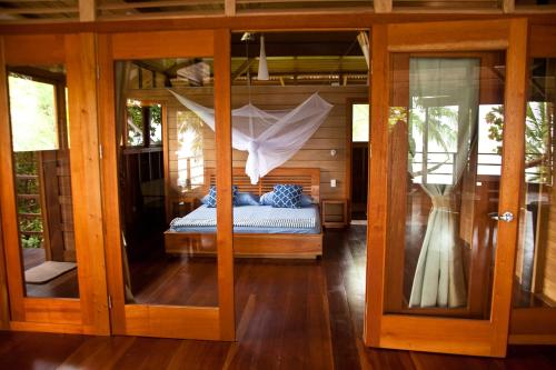 een slaapkamer met een bed en een glazen deur bij Residencia Natural in Bocas del Toro