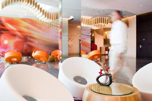 a man walking through a room with white chairs and a table at ibis Mall Avenue Dubai in Dubai