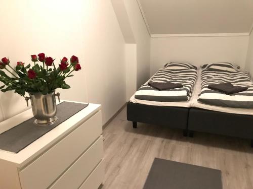 a bedroom with a bed and a vase of red flowers at A Noi Rooms in Kragerø