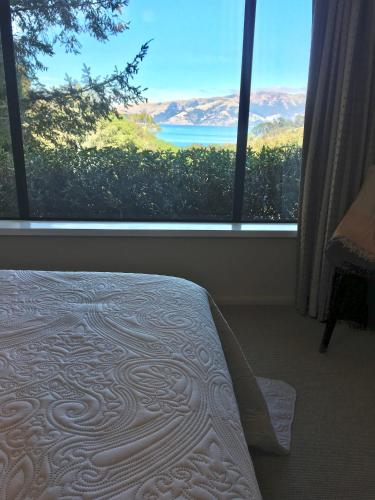 a bedroom with a bed and a large window at Cherrywood Cottage in Akaroa