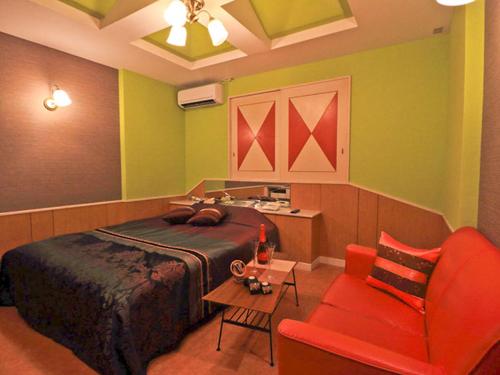 a bedroom with a bed and a red chair at Hotel Sen (Love Hotel) in Mizumaki